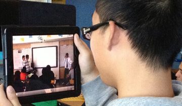 boy holding ipad watching classroom video
