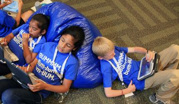 kids laying on ground using tablets