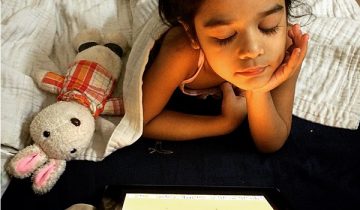 young girl in bed looking at screen