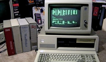 Old computer sitting on desk with green text on screen
