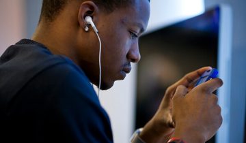 Young African American man looking at smartphone with earphones in his ears