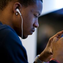 Young African American man looking at smartphone with earphones in his ears