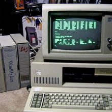 Old computer sitting on desk with green text on screen