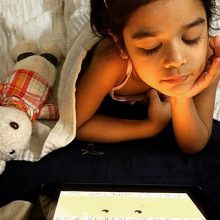 young girl in bed looking at screen