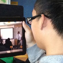 boy holding ipad watching classroom video