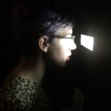Person looks through small opening in dark room